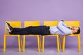 Young man laying down on yellow chairs looking upwards