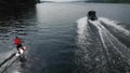 A young man rides a wakeboard. A sports guy rides on the water on a board behind a boat. Top view from a drone. Royalty Free Stock Photo