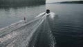 A young man rides a wakeboard. A sports guy rides on the water on a board behind a boat. Top view from a drone. Royalty Free Stock Photo