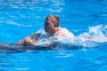 A young man is riding dolphin, boy swimming with dolphin in blue water in water pool, sea, ocean, dolphin saves a man close up Royalty Free Stock Photo