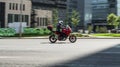 Young man riding fast on red motorbike Ducati. Rider in black clothes and a white helmet, driving on city street on a sunny day Royalty Free Stock Photo