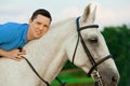 Young man riding a horse at sunset on the beach. Man with a horse in the rays of the sun by the sea. Royalty Free Stock Photo