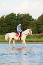 Young man riding a horse at sunset on the beach. Man with a horse in the rays of the sun by the sea. Royalty Free Stock Photo