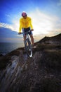 Young man riding moutain bike mtb on land dune against dusky sky