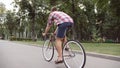 Young man riding vintage bicycle at the park alley. Sporty guy cycling outdoor. Healthy active lifestyle. Rear Back view Royalty Free Stock Photo