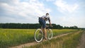 Young man riding vintage bicycle at the rural road over field. Sporty guy cycling along country trail outdoor. Male Royalty Free Stock Photo