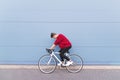 man riding a white highway on a background of a blue wall. Stylish hipster cyclist riding a bike around the city Royalty Free Stock Photo