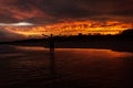 Young man rising hands in the air because he is happy, with a colorfull sunset in the background at Noosaville beach Royalty Free Stock Photo