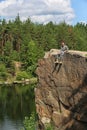 Young man on rock near lake and forest Royalty Free Stock Photo