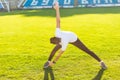 Young man runner stretching his leg on race track in stadium, preparing for working out. Indian man exercising outdoors wearing