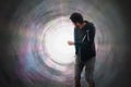 Young man is running away from bright light rays inside tunnel. Royalty Free Stock Photo