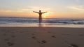 Young man running on beach to the ocean at sunset and raised hands. Sporty guy going on sandy shore to the sea during
