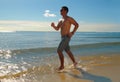 Young man running or jogging on the seachore Royalty Free Stock Photo