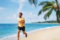Young man running on the sea shore of tropical beach Royalty Free Stock Photo