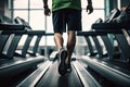 Young man running on a treadmill in a modern gym. Toned image, man walking on treadmill at fitness gym club, top section cropped, Royalty Free Stock Photo