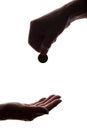 Young man`s hand with a coin gives alms - silhouette, help Royalty Free Stock Photo