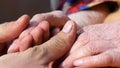 A young man`s hands comforting an elderly pair of hands of grandmother outdoor close-up.Sun comes out from behind the Royalty Free Stock Photo
