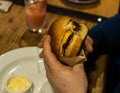 Young man`s hands are holding a bitten hamburger in a fast food restaurant