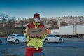 Young Man with Safety Vest Holding Arrow Direction Sign in Parking Lot