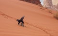 Young man sand dune surfing wearing bisht - traditional Bedouin coat. Sandsurfing is one of the attractions in Wadi Rum desert