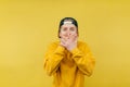 Young man with a scared shocked face covers his mouth with his hands and looks at the camera on a yellow background Royalty Free Stock Photo