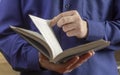 A young man,a schoolboy or a student, holds an open book in his hands,turning the page.