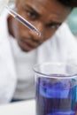 young man scientist using auto-pipette with flask in medical laboratory