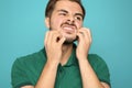 Young man scratching face on color background.