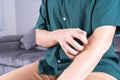 Young man scratching his arm while sitting on sofa at home. Healthcare medical or daily life concept Royalty Free Stock Photo