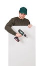 Young man with a screwdriver or electric drill in his hand, stands behind a white panel. Renovation worker before installing Royalty Free Stock Photo