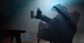 Young man seen from below jumping on a floating chair in his dark room using virtual reality goggles with blue light. 3D