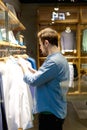 Young man selecting shirts to buy at shop Royalty Free Stock Photo