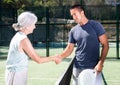 Young man and senior woman handshaking after padel tennis match