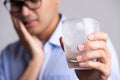 Young man with sensitive teeth and hand holding glass of cold water with ice. Healthcare concept Royalty Free Stock Photo