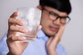 Young man with sensitive teeth and hand holding glass of cold water with ice. Healthcare concept Royalty Free Stock Photo