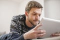 Young man looking at a tablet computer while lying on the couch. Royalty Free Stock Photo