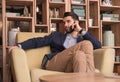 Young man serious listening phone sitting sofa indoors interior Royalty Free Stock Photo