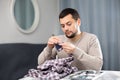 Young man sewing on buttons on sleeve of shirt at home table