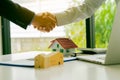 Young man shaking hands with real estate agents in the office and A close-up house plan above the dealer offers a list of home pri