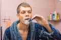 Young man shaving in front mirro