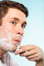 Young man shaving using razor with cream foam. Royalty Free Stock Photo