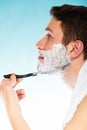 Young man shaving using razor with cream foam. Royalty Free Stock Photo
