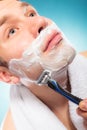 Young man shaving using razor with cream foam. Royalty Free Stock Photo