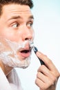 Young man shaving using razor with cream foam. Royalty Free Stock Photo