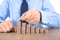 Young man in shirt and tie is stacking dollar coins