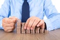 Young man in shirt and tie is stacking dollar coins