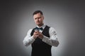 Young man in shirt and waistcoat watch his poker cards, studio shot