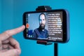 A young man shoots a video on a smartphone while reading text from a teleprompter on a screen Royalty Free Stock Photo