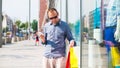 Young man shopping in the mall with many colored shopping bags in his hand. He is holding a phone. Royalty Free Stock Photo