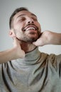 Young man with a short beard touches his neck in a moment of relaxation Royalty Free Stock Photo